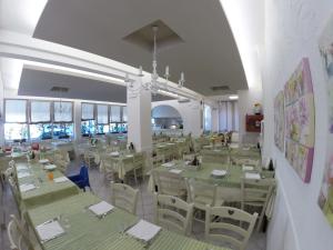uma sala de jantar com mesas verdes e cadeiras brancas em Hotel Astra em Cattolica