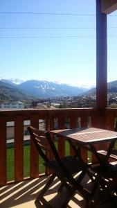 d'une table et d'une chaise en bois sur un balcon avec vue. dans l'établissement Les Olympiades, à Bourg-Saint-Maurice