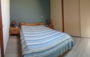 - une chambre dotée d'un lit avec une couverture rayée bleue et blanche dans l'établissement Les Olympiades, à Bourg-Saint-Maurice