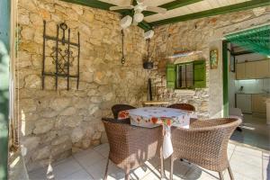 ein Esszimmer mit einem Tisch, Stühlen und einer Steinmauer in der Unterkunft Apartment Julia in Veli Lošinj