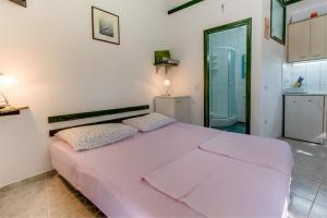 a large pink bed in a room with a kitchen at Apartment Julia in Veli Lošinj