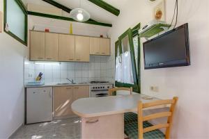a kitchen with a table and a tv on the wall at Apartment Julia in Veli Lošinj