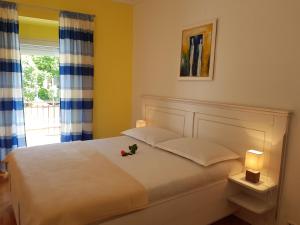 a bedroom with a white bed with two lamps and a window at Apartments Skiljan in Crikvenica