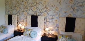 a bedroom with two beds and a wall with flowers at Englands Rose in Thame