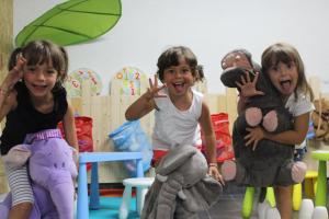 three young girls sitting in a play room with stuffed animals at Hotel Astra in Cattolica