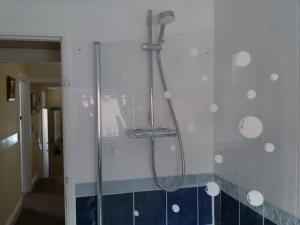 um chuveiro numa casa de banho com azulejos azuis e brancos em St Hilda Guest House em Bridlington