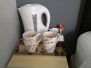 dos tazas blancas en un estante con una jarra blanca en St Hilda Guest House, en Bridlington