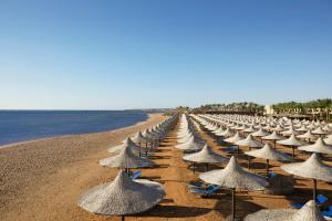 a row of straw umbrellas on a beach at Jaz Mirabel Resort in Sharm El Sheikh