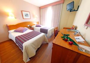 una habitación de hotel con 2 camas y una mesa con flores en Maria de Luna, en Segorbe