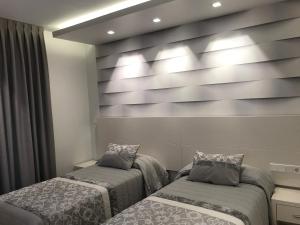 una camera con due letti e una parete con luci di Apartamentos Apolo a Madrid
