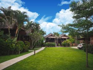 a lawn in front of a house with palm trees at Pai Homey in Pai