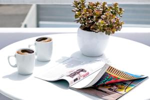a table with two cups of coffee and a magazine at Santorini Blue Senses Villas in Mesaria