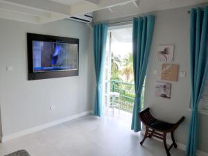 a living room with blue curtains and a tv at Beach Two Bedroom Loft Suite E29 in Ocho Rios