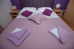 a bed with purple towels and pillows on it at Apartment Nekić in Zadar