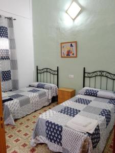 a room with two beds with blue and white sheets at Hostal Villa Mercedes in Chipiona