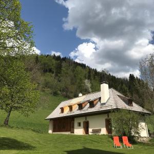 a house with two red chairs in front of it at Klösterle Haus Resi in Arriach