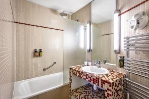 uma casa de banho com um lavatório e uma banheira em Etoile Park Hotel em Paris