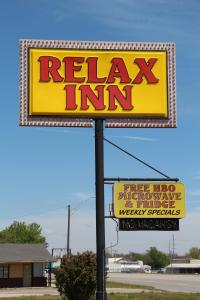 a yellow sign for a relax inn with a sign for a restaurant at Relax Inn Vinita in Vinita