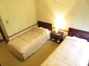 a hotel room with two beds and a table with a lamp at Nikko Pension L'escale in Nikko