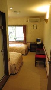 una camera d'albergo con due letti, una scrivania e una finestra di Nikko Pension L'escale a Nikko