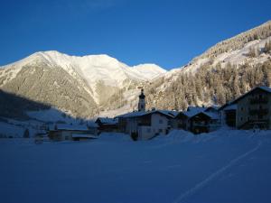 a village in the snow with mountains in the background at Ferienwohnungen Steidl in Innervillgraten