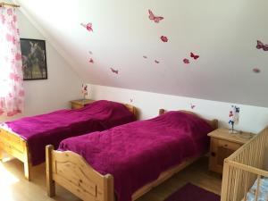 クルムホルンにあるFerienhaus Nordseeのベッドルーム1室(紫のシーツと蝶が壁に飾られたベッド2台付)