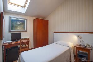 a bedroom with a bed and a desk with a computer at Hotel Blumen in Bologna