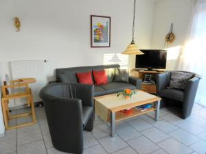 een woonkamer met een bank, 2 stoelen en een tafel bij Ferienhaus Seehund in Krummhörn