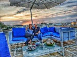 a man and woman sitting on a couch under an umbrella at Le Terrazze in Otranto