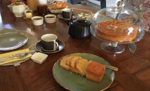 a table with a plate of bread and a cake at Au Bord de La Dhuy in Orges
