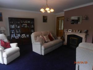 sala de estar con 2 sillas, sofá y chimenea en Larkfield House B&B, en Killarney