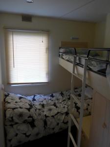 マーブルソープにあるMablethorpe L12 Caravanのベッドルーム1室(二段ベッド2台、窓付)が備わります。