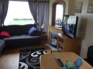 a living room with a couch and a flat screen tv at Mablethorpe L12 Caravan in Mablethorpe