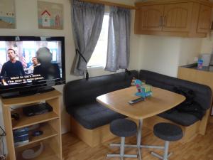 a living room with a couch and a table and a tv at Mablethorpe L12 Caravan in Mablethorpe