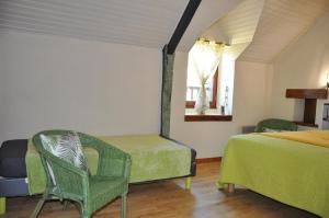 a bedroom with two beds and a chair and a window at Perrault Gites in Loscouët-sur-Meu