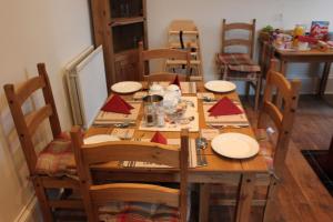 a wooden table with chairs and a long table with red napkins at Carrick Farm in Lochgoilhead