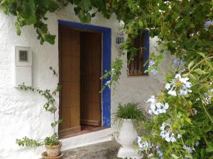 uma porta aberta de um edifício branco com flores em Las Parras em Rute