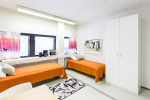 2 łóżka w białym pokoju z pomarańczową pościelą w obiekcie Forenom Hostel Vantaa Airport w mieście Vantaa