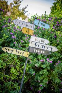 a pole with street signs in front of flowers at Hôtel Le Peu Breton in Sainte-Marie-de-Ré