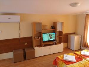 una sala de estar con TV y una habitación con cama en Вили Бийчхаус, en Kranevo