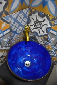 lavabo azul con grifo de oro en el baño en Hostal Sole, en Santa Ana