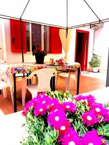 a patio with a table and some pink flowers at Garden House Airport in Naples