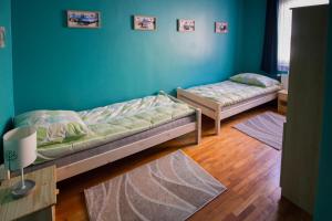 two beds in a room with blue walls and wooden floors at Boros Vendégház Eger in Eger