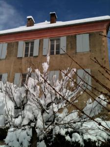 a house with snow on the branches of a tree at "Le Château" in La Roche-des-Arnauds