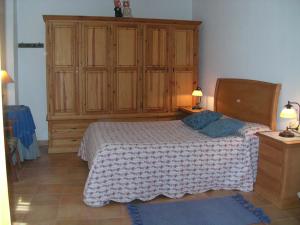 1 dormitorio con 1 cama y un gran armario de madera en La Casa Del Valle en Cortijos Nuevos
