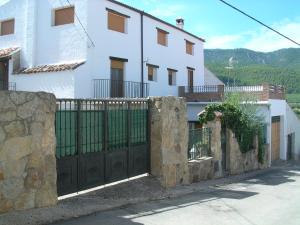 uma cerca em frente a uma casa branca com um portão em La Casa Del Valle em Cortijos Nuevos