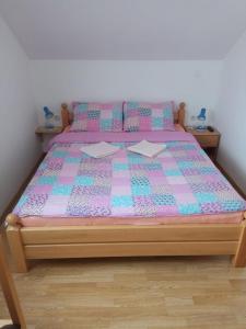 a bed with a pink and blue quilt on it at Apartments Dale in Smoljanac