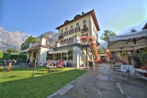 a large building with a patio with chairs and tables at Villa Novecento Romantic Hotel - Estella Hotel Collection & Experience in Courmayeur