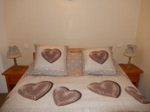 Una cama con tres almohadas de corazón. en Gîte Les Guérins, en La Bâtie-Neuve