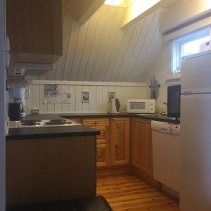 uma cozinha com armários de madeira e um frigorífico branco em Kjekstadveien 22 Homborsund em Jordtveit